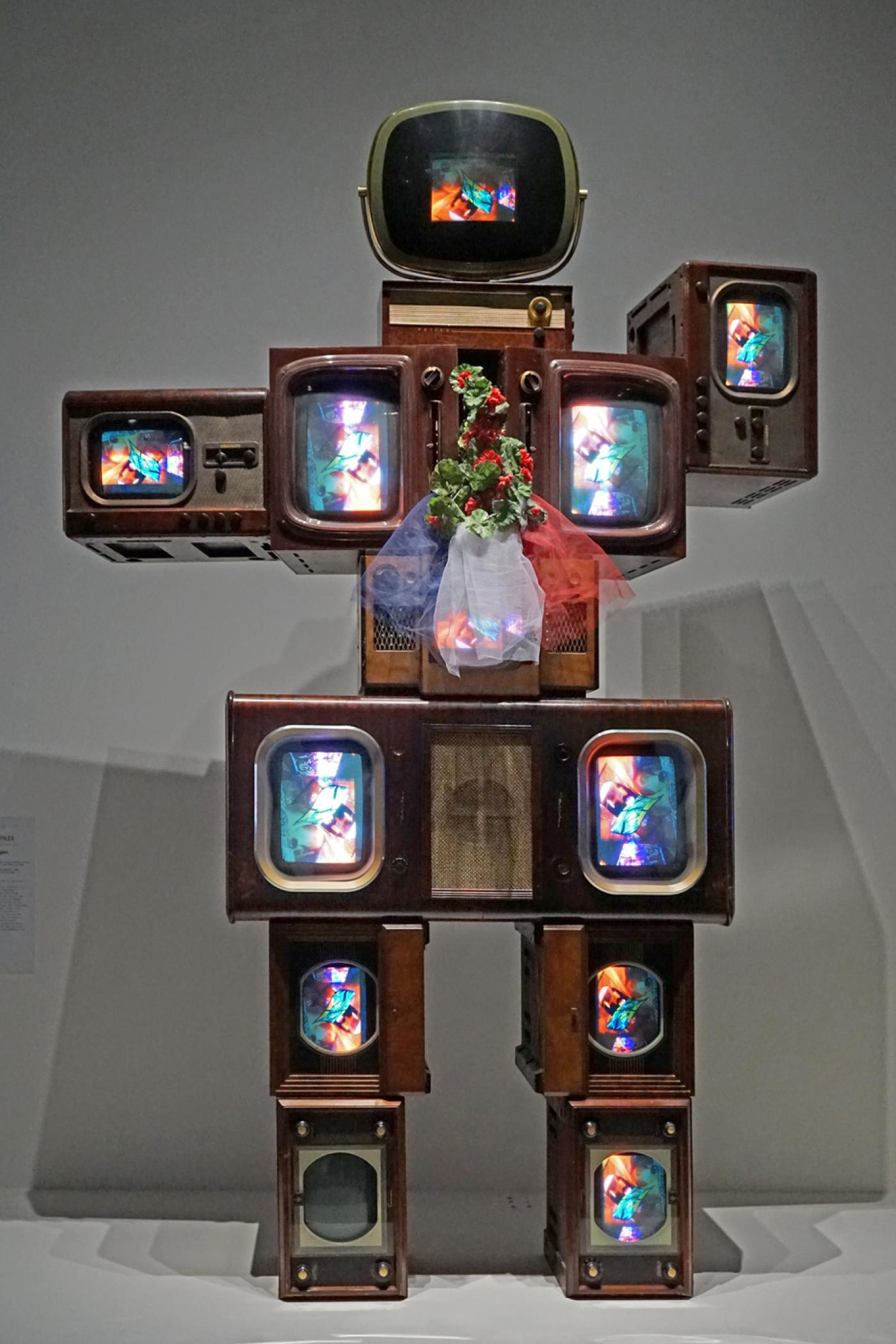 Nam June Paik, Olympe de Gouges, 1989, 12 postes de TV en bois, 12 moniteurs couleur, lecteur de vidéodisque, tulle, fleurs en tissu.