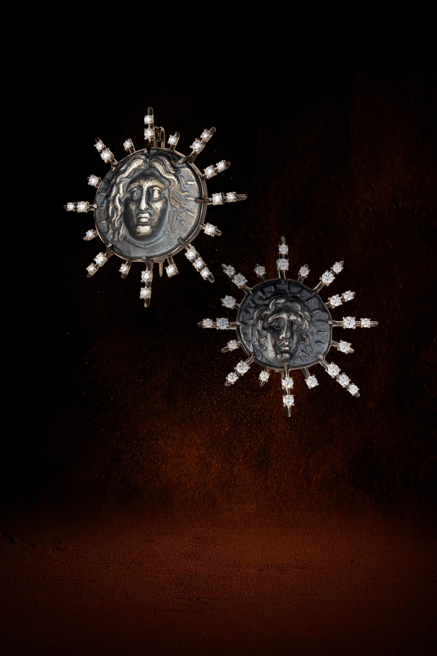 Broches Helios, "Paire de broches", Ve siècle avant J.-C., or noir 18K, serties de diamants, centrant un tétradrachme, drachme d'argent représentant le dieu solaire Hélios, Rhodes. Maison Auclert.