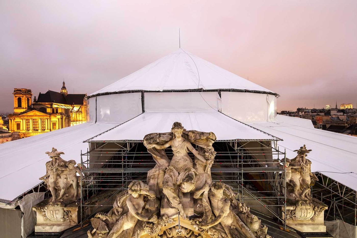 Les sculptures surmontant le fronton de la Bourse de commerce, devant la coupole en restauration.