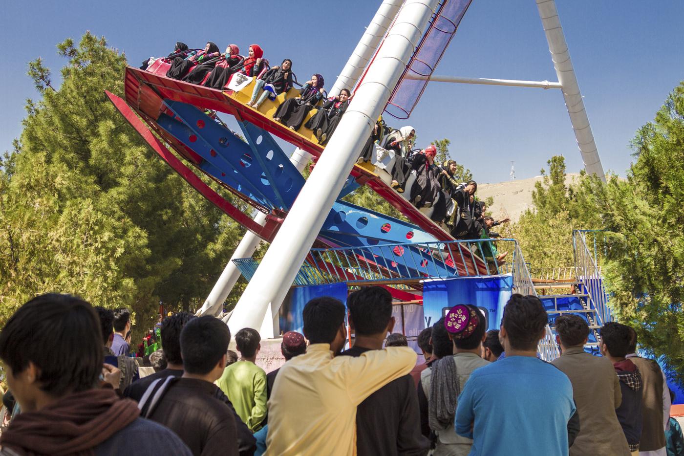 De jeunes hommes admirent le courage et l’excitation des jeunes femmes installées dans une attraction du parc Takht-e-Far à Hérat. Photographie de Morteza Herati, prise avant le retour au pouvoir des Talibans.