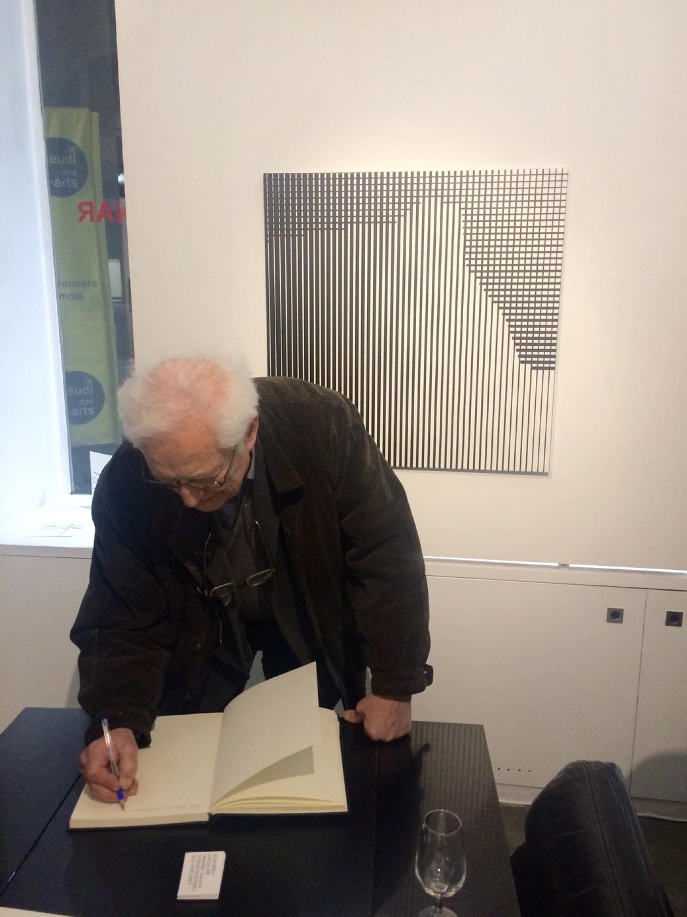 L'artiste Alexandre Hollan signant le Livre d'Or  de l'exposition.